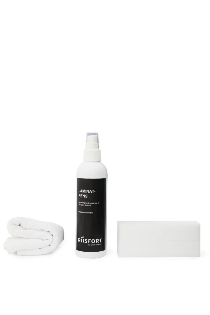 Sort sprayflaske med laminatrens ved siden af en hvid svamp og en foldet hvid klud